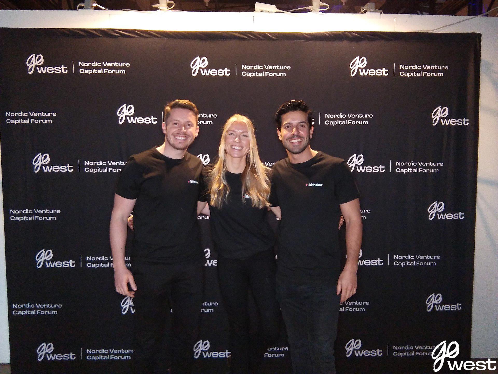 Niklas Busck, Julia Sjövall and Poyan Karimi standing in front of the Go West photo wall