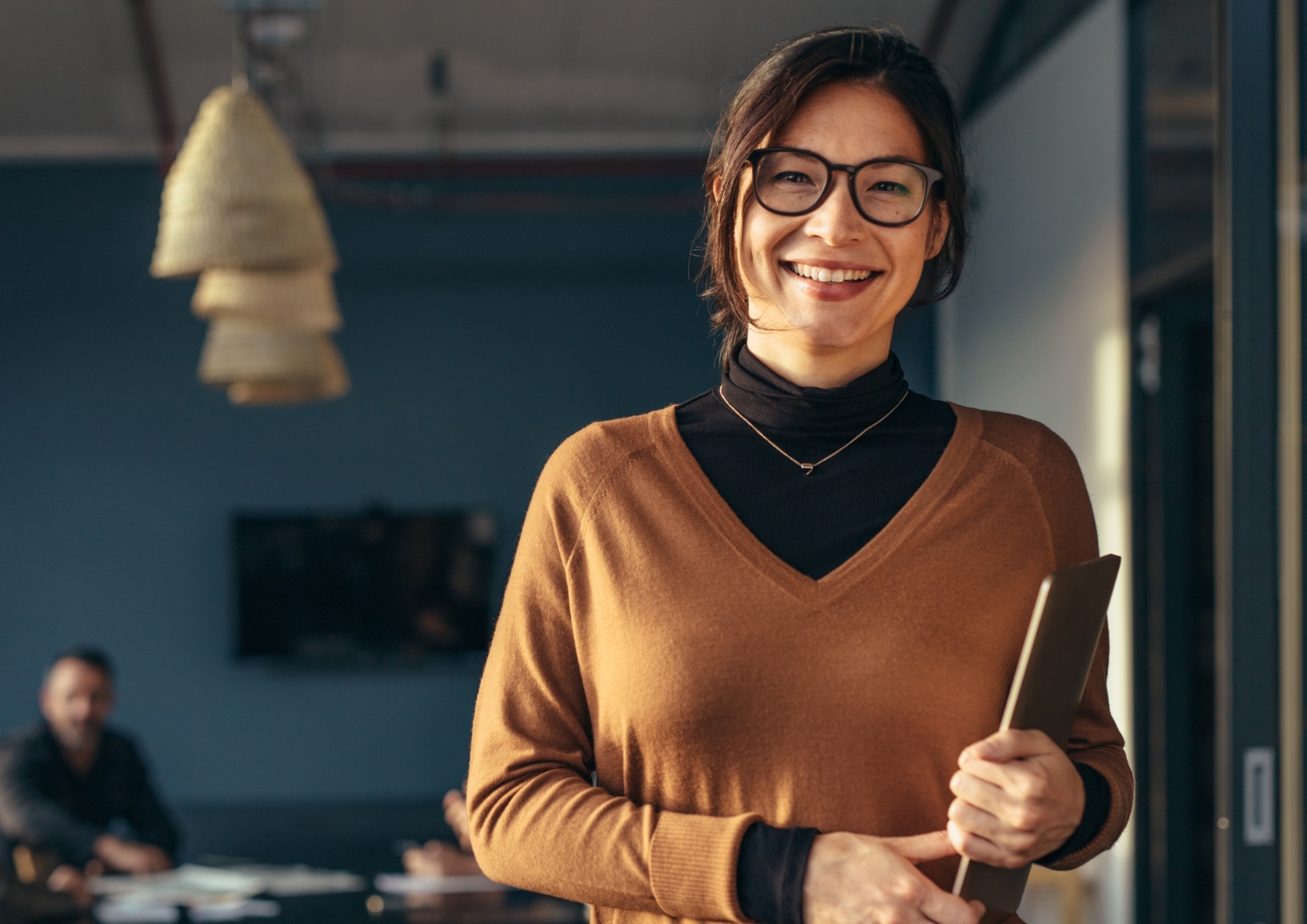 a person with glasses holding a laptop smiling